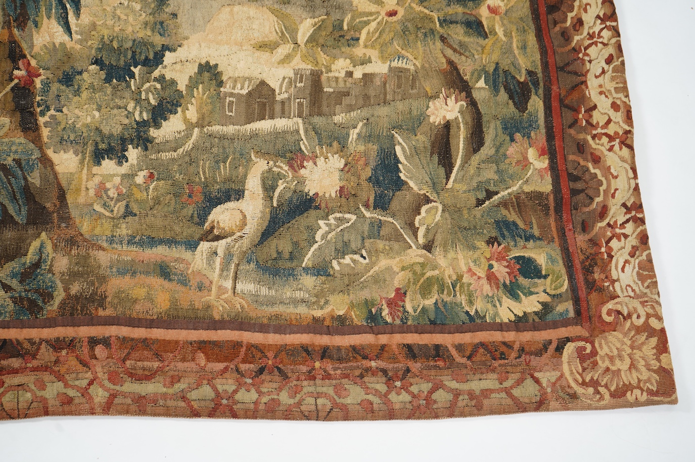 A mid to late 18th century French Aubusson tapestry of a bird, possibly a heron, within a tree lined verdure garden scene to a chateaux, with an ornate rust coloured contrasting tapestry border.201cm x 170 cm. Condition
